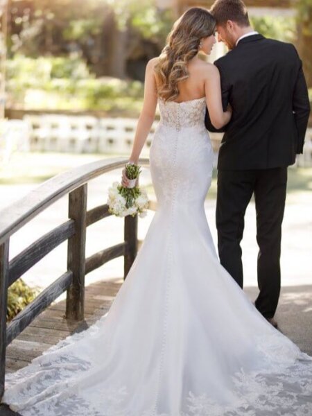 Essense of Australia D2812 plain mermaid wedding dress with beaded lace detail and statement train back view with groom.