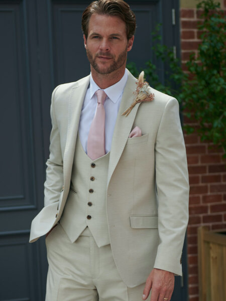 Peter Posh grooms e piece hire suit in soft light weight pale stone fabric close up front.