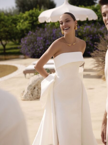 Modeca Genesis fitted wedding dress available in our Huddersfield boutique in plain mikado with fitted bandeau neckline and optional bow on the A line train available in our Huddersfield Boutique West Yorkshire.