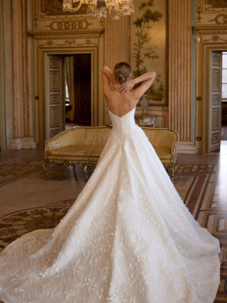 Randy Fenoli Ivy wedding dress with plain basque bodice optional drop drape sleeves and trailing leafy lace over an A-line skirt strapless back view.