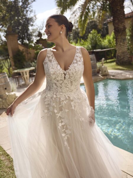 Modeca Curve collection Jolanthe plus size A line wedding dres with lace detail trailing from the V neck bodice onto the plain soft tulle skirt close up front view.