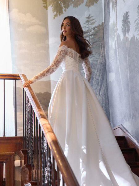 Essense of Australia D4457 plain ballgown wedding dress with rouched basque bodice with lace inset to the Bardot neckline and off the shoulder lace sleeves back view.
