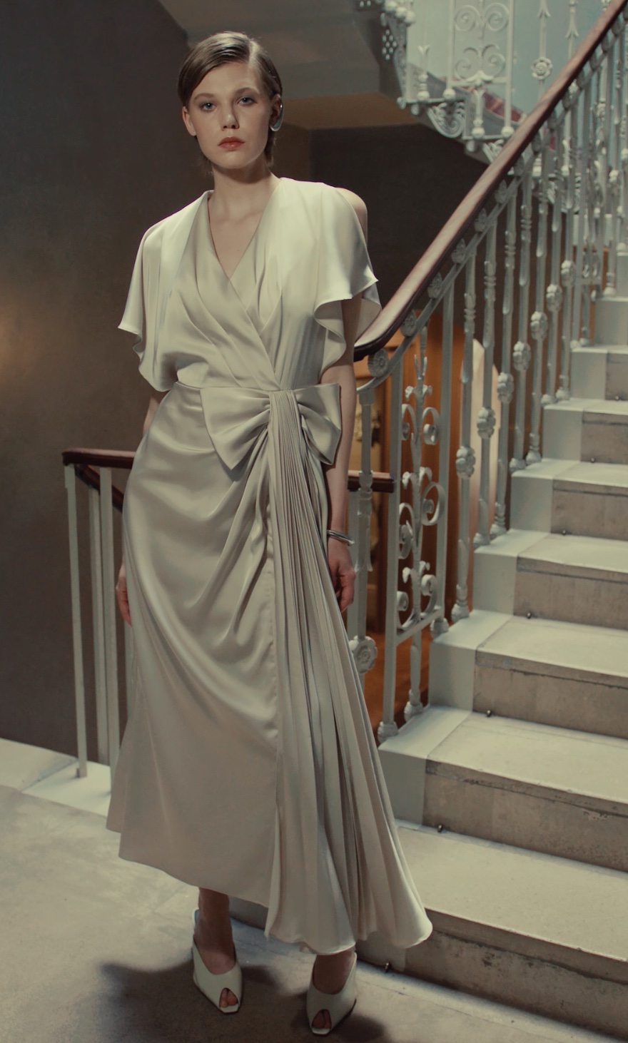 Maisonel 3116 pastel green mother of the bride dress with V neckline flutter sleeves and statement bowModern, elegant occasion wear for weddings, the races, cruises and black tie events front view with videomatching hats, shoes and bags available. 