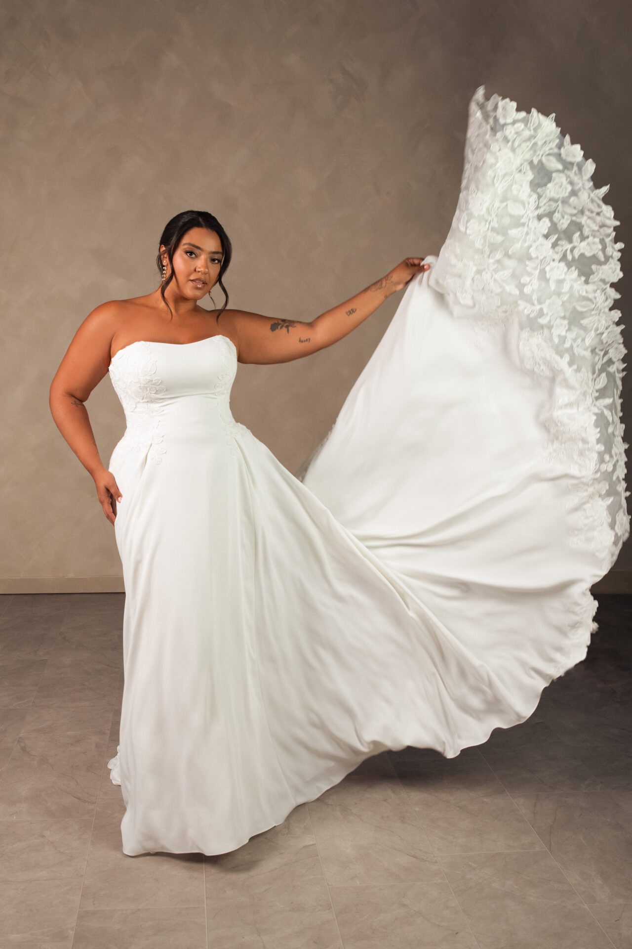 Essense of Australia D4504 Aline wedding dress in plain liquid crepe with some lace detail front view holding train.