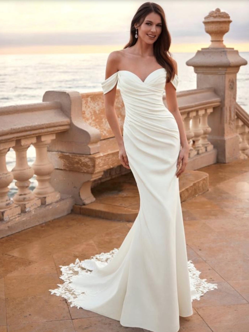 Enzoani plain fitted wedding dress with flattering rouched silhouette drop straps & statement train with lace edging.